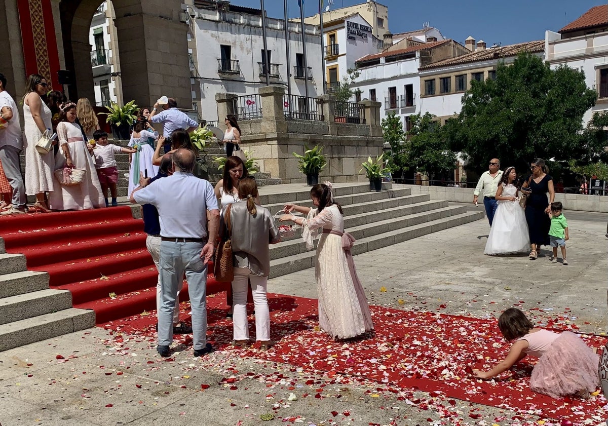 Imagen principal - Los pequeños recogen pétalos ante el altar. En Santa María la procesión y las enseñas de las cofradías se encontraron con el material del festival de teatro. María Reyes Torres, de nueve años, posa con sus padres y abuelos en la Plaza Mayor de Cáceres.
