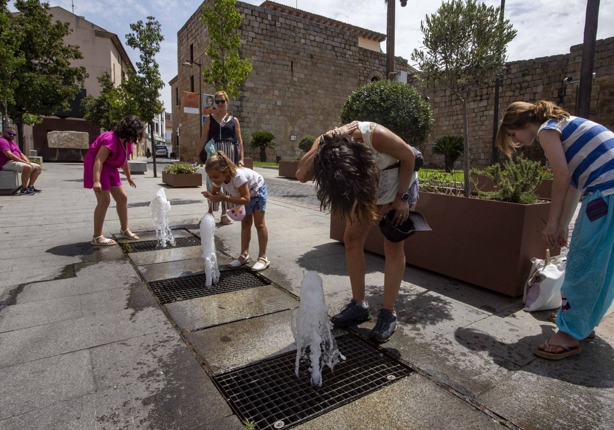 Unos turistas se refrescan junto a unas fuentes en el entorno de la Alcazaba de Mérida.