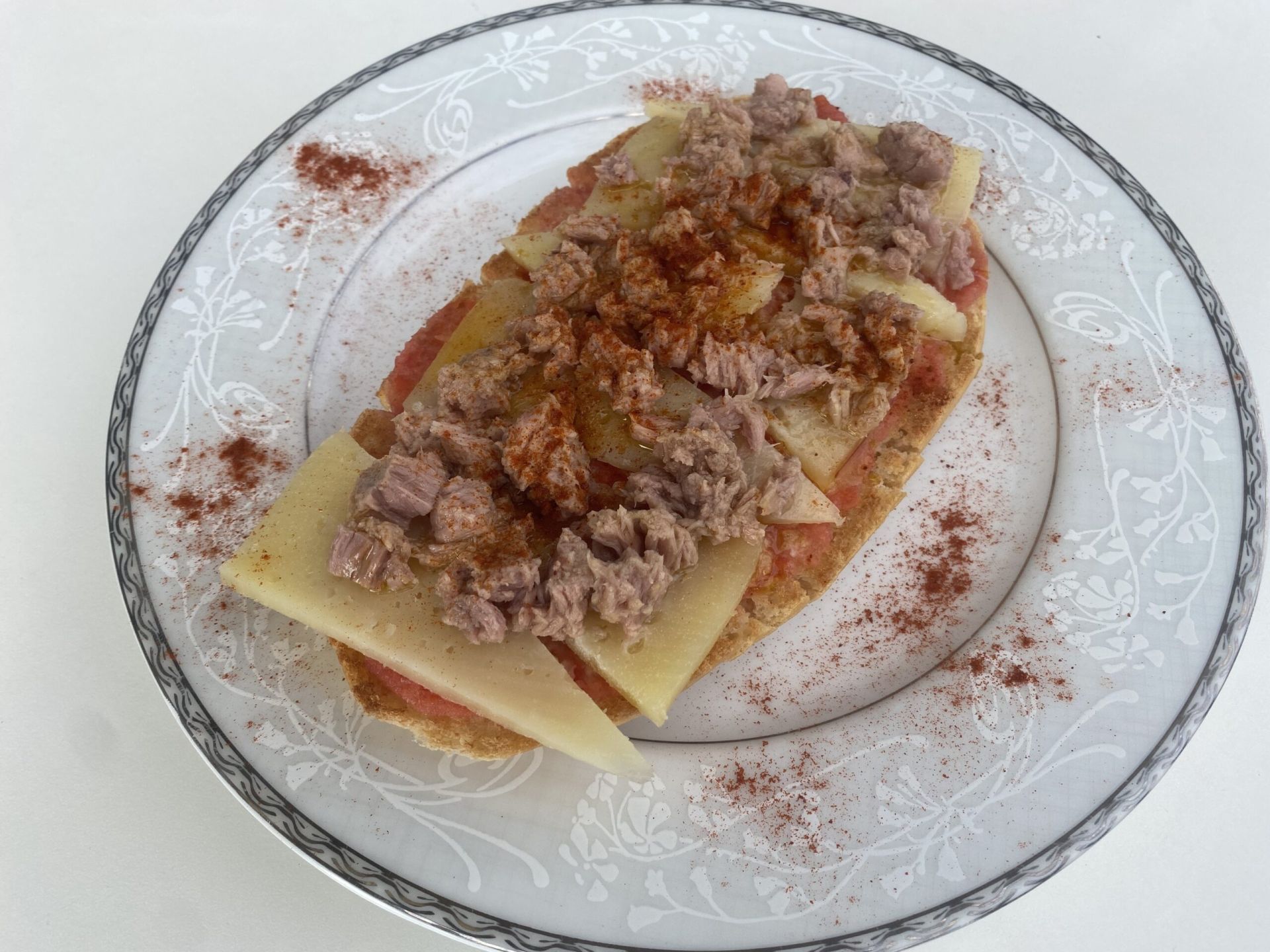 Tostada nutritiva con base de tomate, queso curado, atún, aceite de oliva y perejil