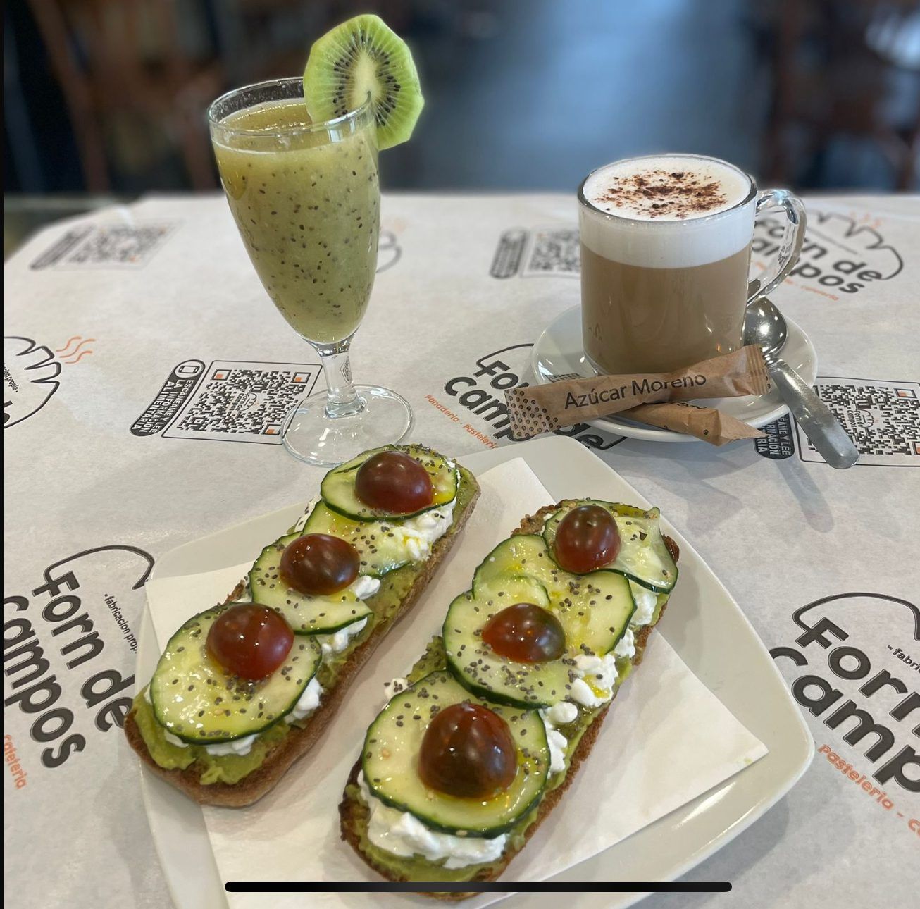 Tostada hecha sobre pan de centeno, con una base de guacamole, queso cottage, pepino marinado, tomate cherry , AOVE ecológico de la tierra y semillas de chía. Acompañado de un zumo de kiwi y piña y un cafe o infusion