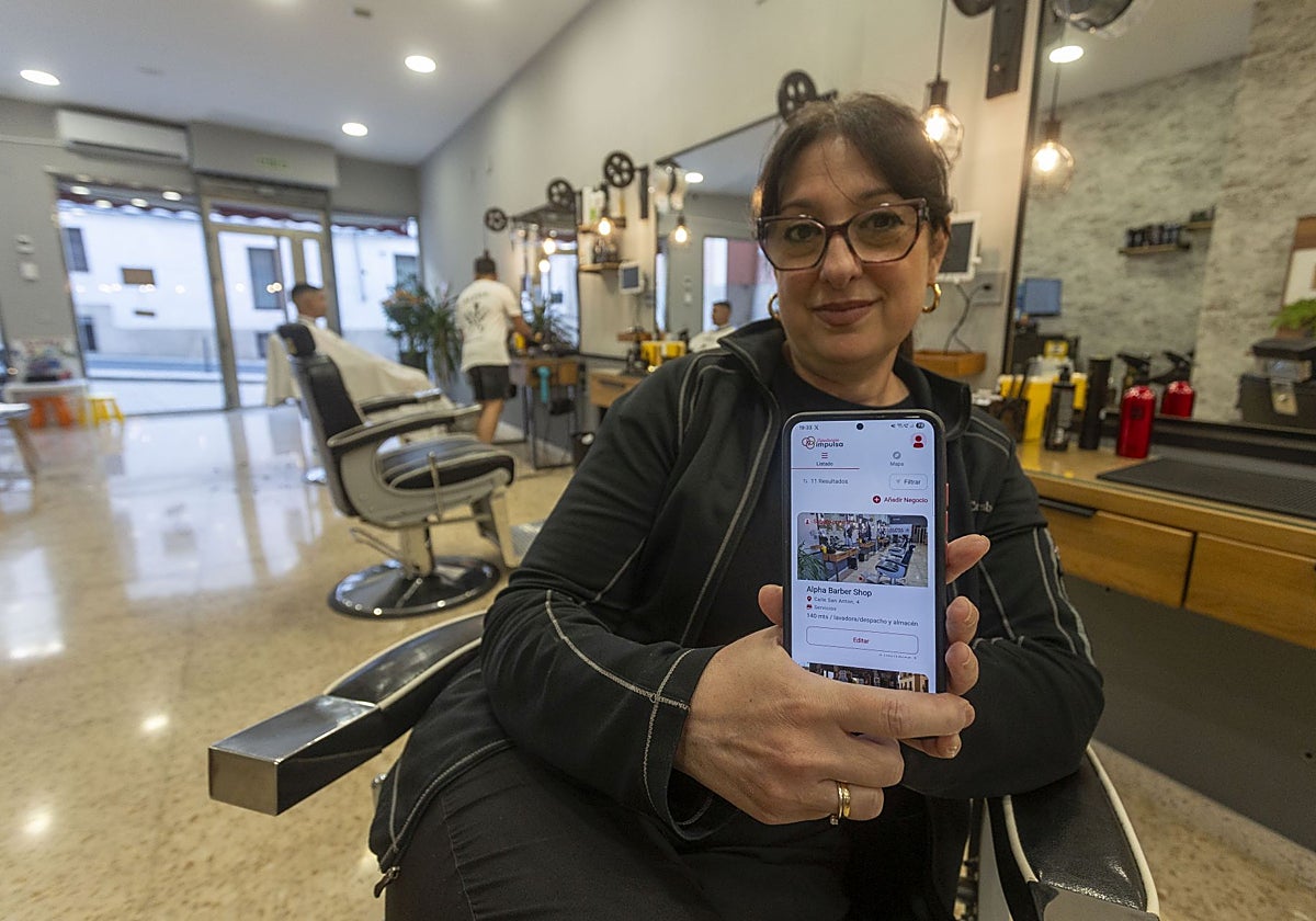 Lorena Mayz en su barbería de Cáceres mientras muestra la aplicación de Diputación Impulsa.