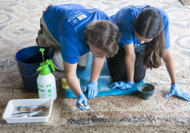 Dos alumnas en la restauración de las teselas de un mosaico.