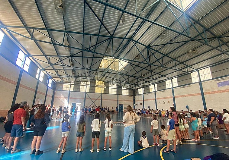 Los monitores del campamento evacuado por el incendio realizan actividades en el pabellón en el que están realojados para distraer a los menores.