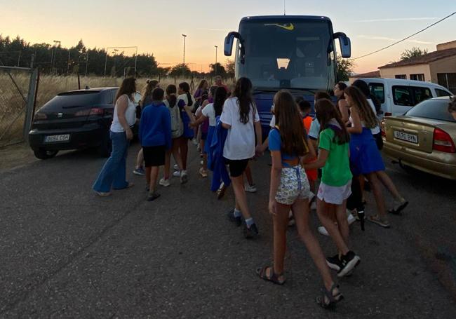 Los jóvenes del camping desalojado montan en un autobús para regresar a última hora de la tarde.