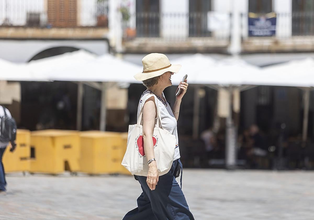 Una mujer con gorro pasea por la Plaza Mayor de Cáceres.