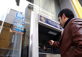 Un hombre saca dinero de un cajero en la calle Santa Eulalia.