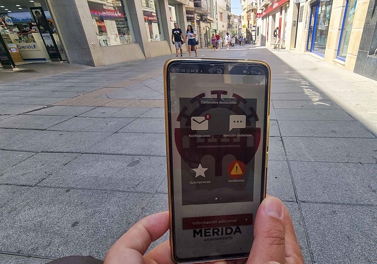 Una persona se dispone a hacer fotos de baldosas en mal estado en la calle Santa Eulalia con la aplicación.