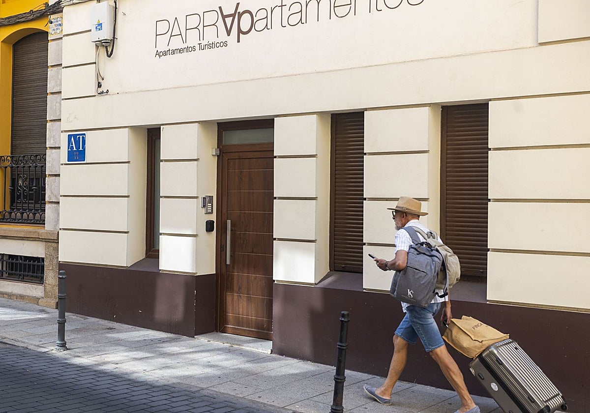 Un viajero pasa delante de un edificio destinado a apartamentos turísticos situado en la calle Parras de Cáceres.
