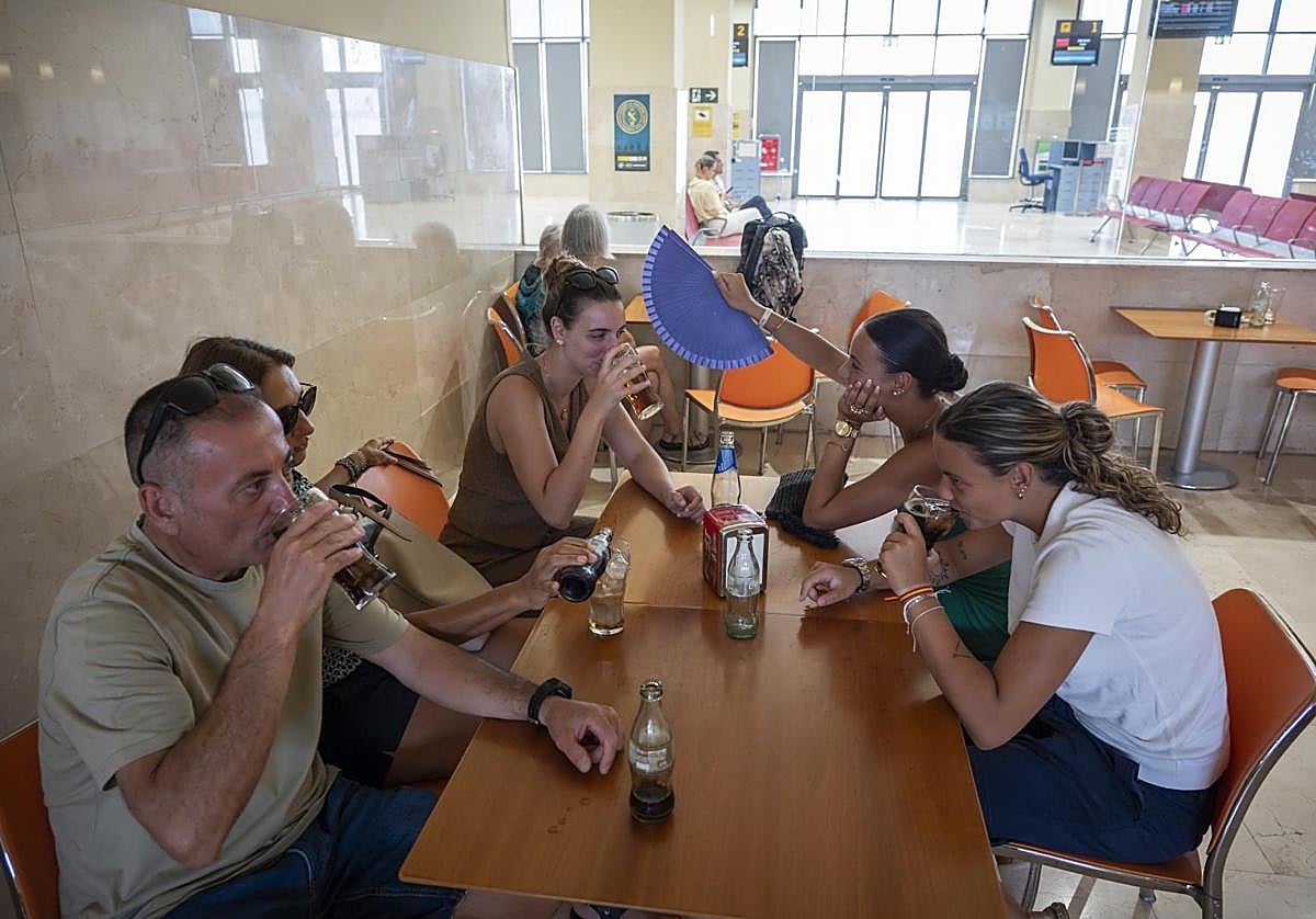 Los pasajeros esperan su avión con refrescos y abanicos en la cafetería del aeropuerto.