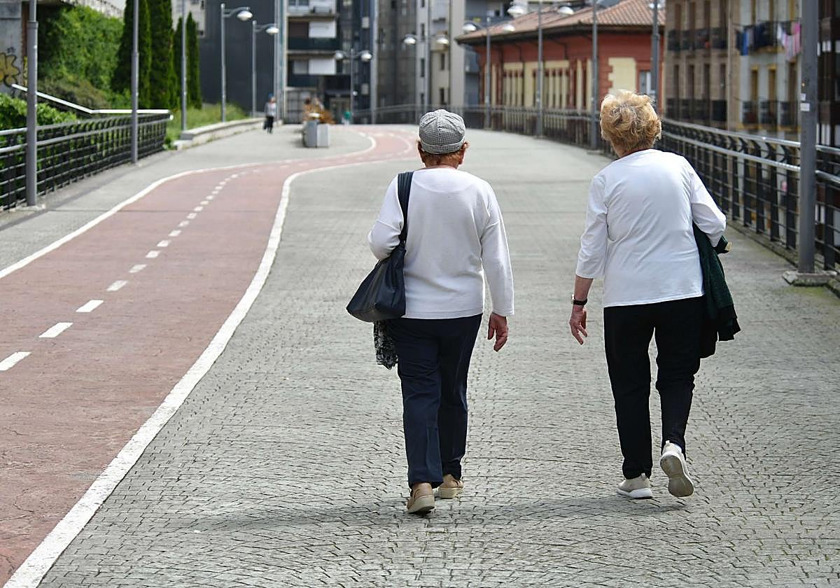 Dos personas mayores pasean por la calle.