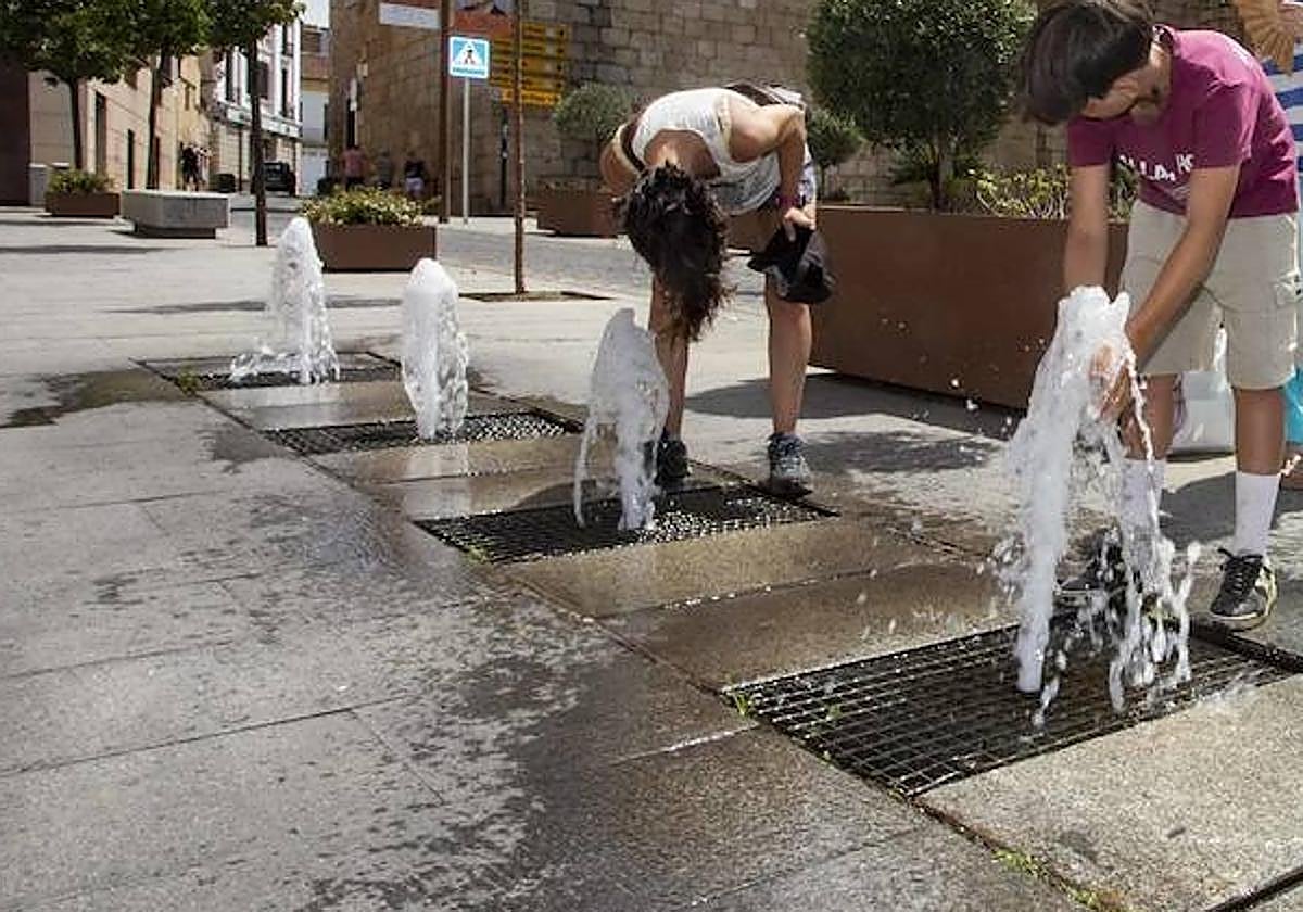 Imagen de archivo de dos jóvenes refrescándose en una fuente en Mérida.