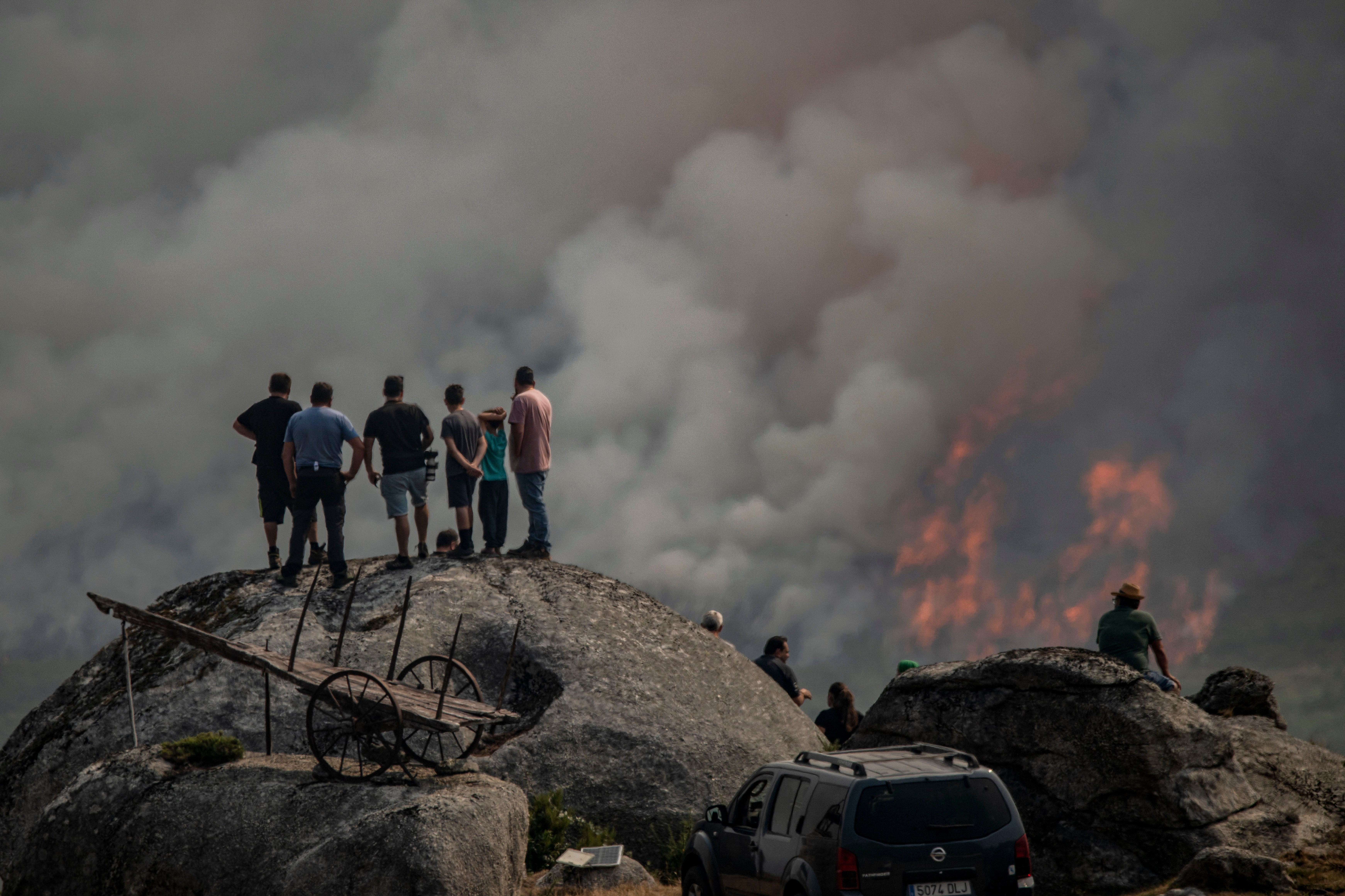 Varias personas observan el incendio forestal declarado en Avión (Ourense) este lunes 25 de agosto.