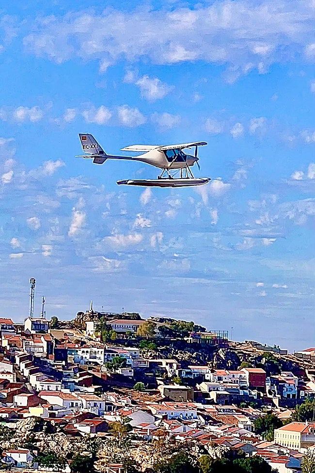 Un hidroavión y el pueblo de Alange al fondo.