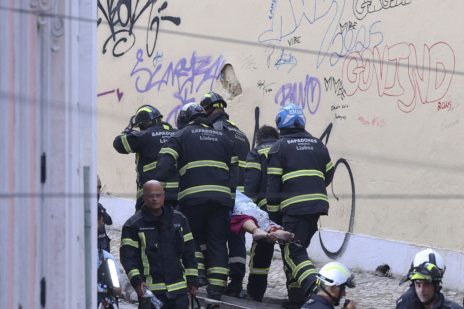 Los bomberos de Lisboa trasladan a una víctima del fatal accidente. 