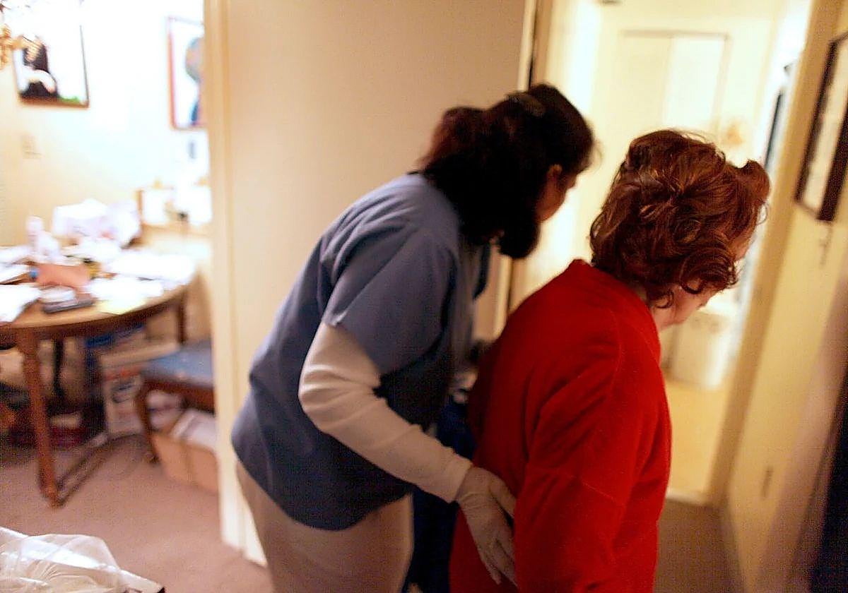 Una cuidadora ayuda a una persona mayor en una imagen de archivo.