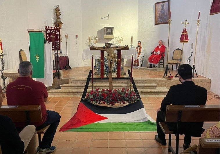 El párroco del Espíritu Santo coloca la bandera palestina a un Cristo durante una romería en Cáceres