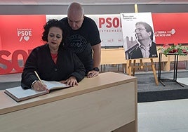 Mercedes Custodio y su marido, Francisco Javier Carreras, firman esta mañana en el libro de condolencias habilitado por el PSOE extremeño en su sede regional, en Mérida.