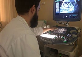 Un ginecólogo analiza una ecografía realizada a una mujer embarazada.