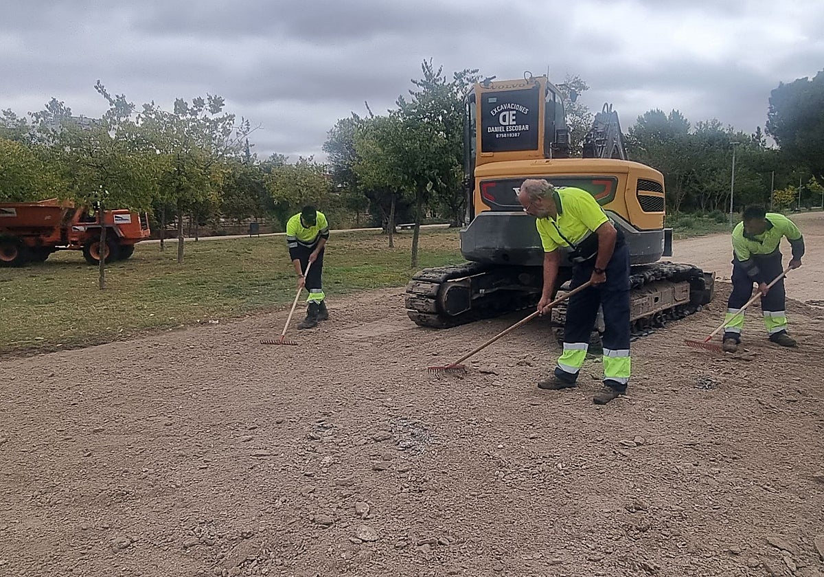 Un grupo de trabajadores repone tierra en el parque de La Isla, junto al río Guadiana.