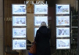 Una mujer mira viviendas en alquiler en una inmobiliaria.