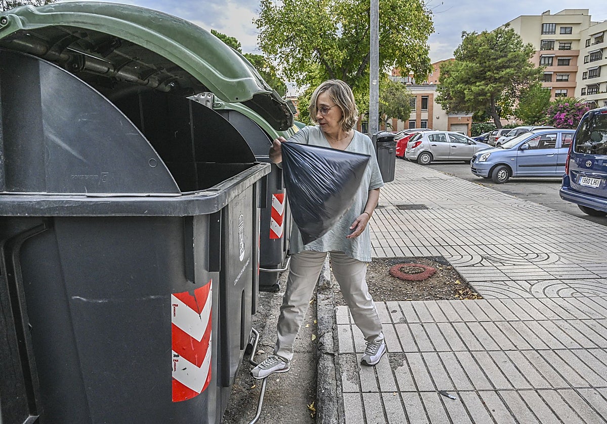 Una mujer tira una bolsa de basura a un contenedor en Badajoz.