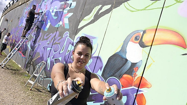 La artista pacense Sheila, junto al tucán que ha dibujado este sábado en la nueva selva del Guadiana.