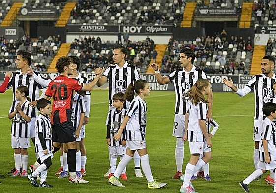 Los chavales de la cantera saltan al césped de la mano de los jugadores del Badajoz antes del comienzo de los partidos.
