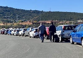 Dos peatones caminan por la calzada a la salida del hospital al estar la acera (a la derecha) ocupada por los coches.