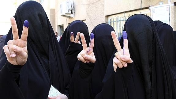 Mujeres muestran, mediante el símbolo de la victoria, su dedo índice marcado tras haber ejercido su derecho al voto en un colegio electoral en Bagdad. 