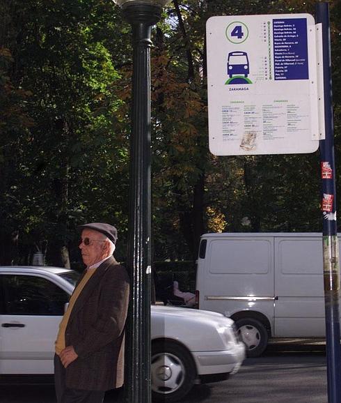 Una persona mayor espera en la parada del autobús. 