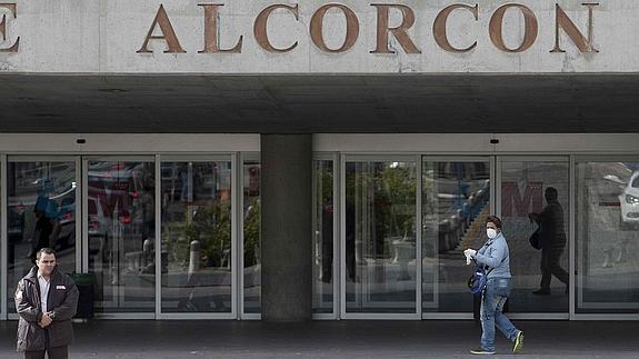 Una persona con mascarilla y guantes entra en el Hospital de Alcorcón.