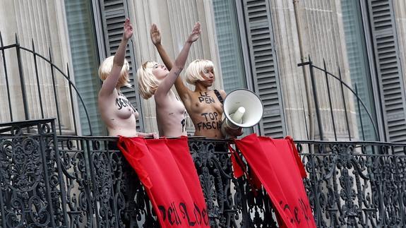 Activistas de Femen protestan, con el eslogan 'Le Pen TOP fascist', desde un balcón durante la marcha por el Primero de Mayo. 