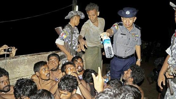 Agentes de la Policía birmana ofrecen agua a un grupo de inmigrantes. 
