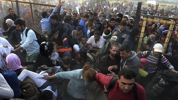 Un grupo de refugiados trata de saltarse un cordón policial.