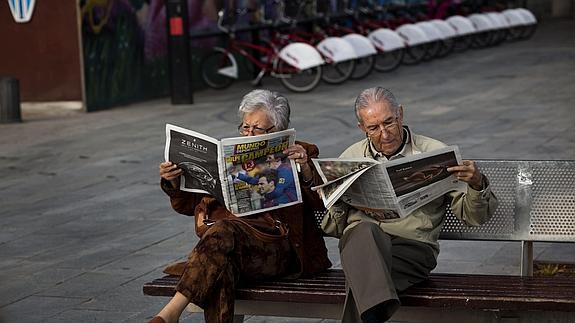 Una pareja de ancianos lee la prensa deportiva en una plaza de Barcelona.