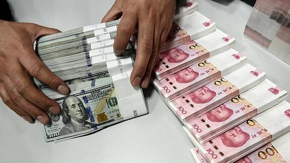 Un empleado cuenta yuan chino y billetes de dólares estadounidenses en una sucursal del Banco de China en Taiyuan.