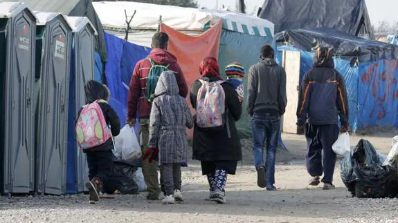 Inmigrantes con sus pertenencias en el campamento de Calais.