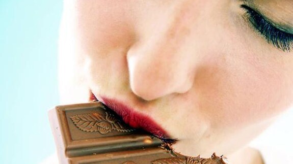 Una mujer muerde un trozo de chocolate
