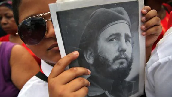Una cubana muestra una foto de Fidel Castro. 