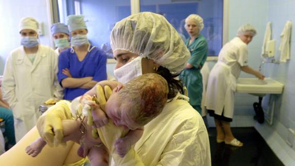 Comadrona sostiene a un niño recién nacido.