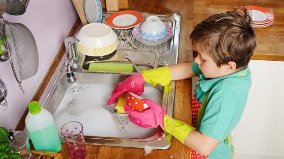 Un niño lavando los platos.
