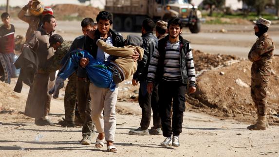 Varias personas se desplazan, vigiladas por las fuerzas iraquíes, en el oeste de Mosul.