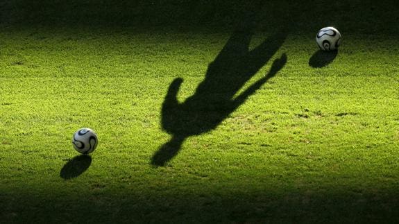 La sombra de un futbolista en un campo de fútbol. 