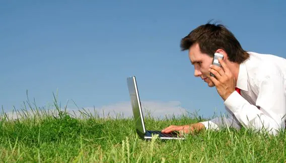 Un hombre habla por teléfono mientras consulta su ordenador. 
