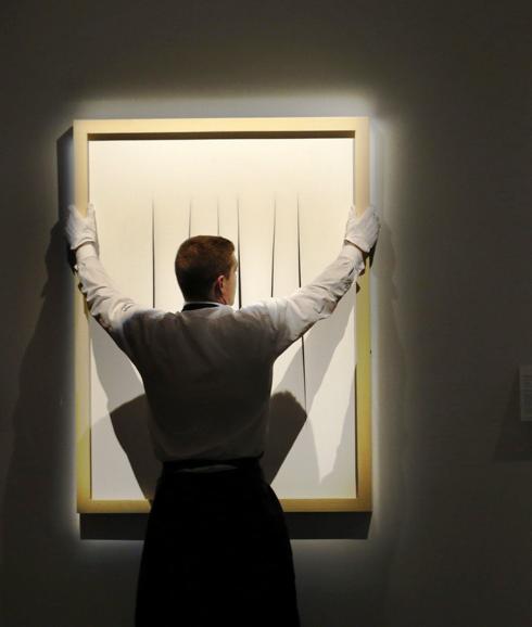 Un empleado de Sotheby coloca una obra de Lucio Fontana.