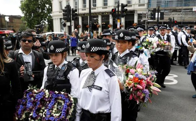 Un grupo de agentes de Policía hace cola para depositar flores en homenaje a las víctimas de los atentados de Londres. 