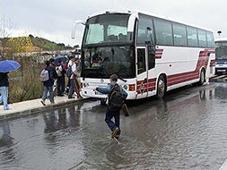 Alumnos del instituto 'Albalat', de navalmoral de la Mata, corren bajo la lluvia para que no se le escape el autobús.|ELOY GARCÍA