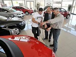Dos compradores estudian las características de un modelo de coche en un concesionario extremeño. / ARNELAS - VÍDEO: B.C.