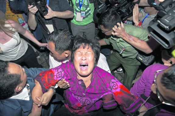 Una mujer, familiar de un pasajero del avión desaparecido, rompe a llorar ante la prensa. 