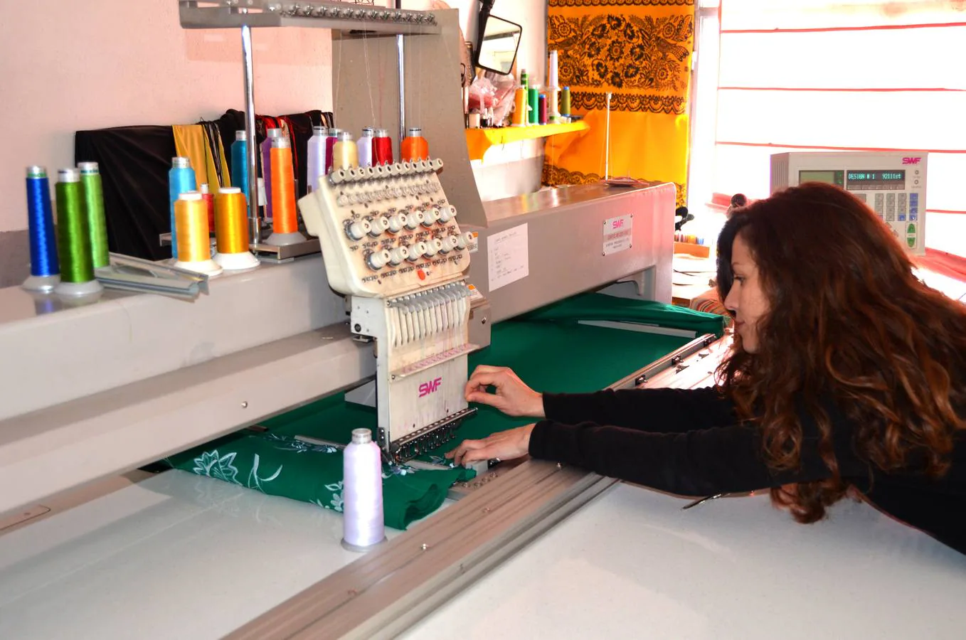 María Rodríguez coloca uno de los hilos en la máquina de bordado